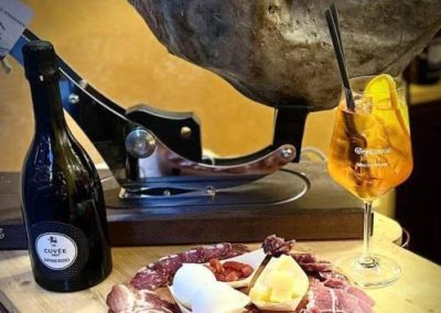 Prosecco as an appetizer accompanied by slices of hand-cut ham.